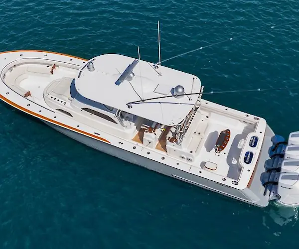 The image shows a large white powerboat with multiple outboard engines, floating on the ocean.